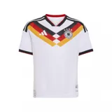 Camiseta de fútbol Adidas de la selección de Alemania, modelo primera equipación 2026. Diseño blanco con detalles en negro, rojo y amarillo que simulan la bandera alemana en el pecho. Incluye logo de Adidas, escudo de la selección y las tres tiras características en los hombros.