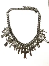 Collar plateado de cadena gruesa con múltiples dijes de cruces de diferentes estilos.