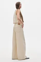 Pantalón jean color crema, de tiro alto y corte wide leg.