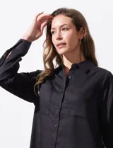 Camisa blanca de lyocell, marca Cyrus. Tiene cuello con solapa, abertura central con botones, mangas largas regulables con presilla y botón, y dos bolsillos delanteros aplicados.
