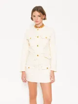 Conjunto de mini falda y chaqueta color crema con botones dorados y costuras en contraste.