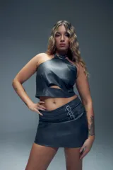 Minifalda en símil cuero negro, con apliques de tiras y hebillas metálicas en el frente.
