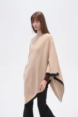 Poncho beige de poliéster con cuello alto y terminaciones en negro.