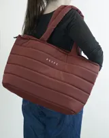Bolso tipo tote bag acolchado color bordó, con asas de hombro tubulares y logo estampado en el frente.