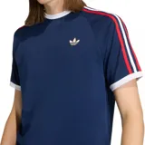 Camiseta Adidas Originals de manga corta, color azul marino, con cuello redondo blanco y ribetes en las mangas. Presenta las tres franjas características en los hombros en rojo, blanco y azul. Lleva el logo del trébol bordado en color beige en el pecho.