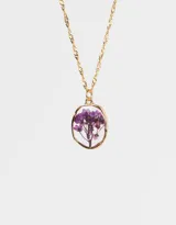 Cadena corta dorada con dije circular transparente que contiene una flor amarilla.