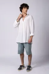 Camisa blanca de lino con cuello clásico, manga larga con puños abotonados y corte holgado. 