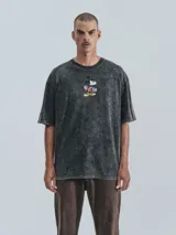 Remera negra con efecto nevado, corte oversize y estampado de Mickey Mouse sobre una patineta.