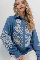 Camisa de denim azul con bordados en color crudo, de corte relaxed, manga larga y botones frontales.