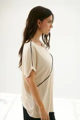 Remera negra de corte holgado con cuello redondo y mangas cortas con dobladillo. Presenta una línea diagonal blanca que cruza el frente desde el hombro hasta la cadera.