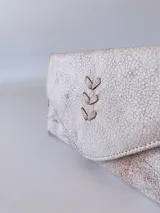 Billetera de cuero color crudo con textura, cierre con broche y monedero externo.