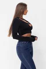 Top negro de lycra con manga larga y corte irregular con aberturas en el escote y detalle de hebilla metálica.