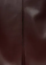 Falda midi de cuero sintético color marrón chocolate, corte recto, tiro alto y abertura frontal.