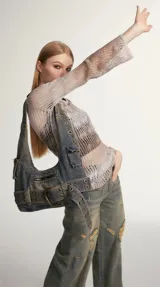 Bolso bandolera de denim azul con múltiples bolsillos y detalles de cinturón con hebilla metálica.