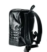 Mochila negra con diseño acolchado de cuadrillé y logo metálico en la parte inferior. Cuenta con un bolsillo frontal con cierre y dos compartimentos principales con cierre. Tiene correas ajustables para los hombros y asa superior para llevar en la mano.