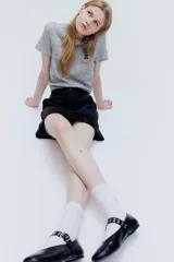Remera gris de punto fino con cuello redondo y mangas cortas. Tiene un pequeño bordado en el pecho.