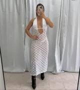 Vestido midi de encaje blanco con transparencias, cuello halter y escote profundo con abertura central. Presenta un diseño ajustado al cuerpo.