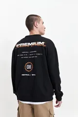 Buzo de felpa negro con estampado en la espalda que incluye la palabra 'Premium' en blanco y naranja, la frase 'Creative Studio' en naranja, y otros textos y gráficos en blanco y naranja. Tiene cuello redondo y puños.