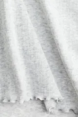 Remera gris jaspeado de punto pointelle suave con escote redondo pronunciado y ribete de encaje. Modelo ajustado con ribete sobrehilado en mangas y bajo.