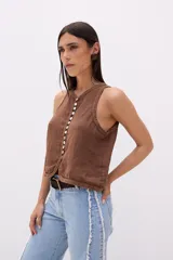 Top sin mangas color beige, con escote en V y cierre frontal de botones de nácar. Presenta costuras decorativas en el borde del escote y sisas.