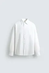 Camisa blanca de algodón con estructura twill, corte regular, cuello solapa, manga larga con puños abotonados y cierre frontal con botones.