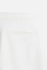 Pantalón de jogging color beige confeccionado en tejido de mezcla de algodón. Cuenta con cintura elástica ajustable con cordón, bolsillos frontales y traseros.