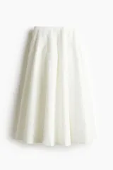 Falda evasé blanca con textura, tiro alto, flecos decorativos y pliegues de caja.