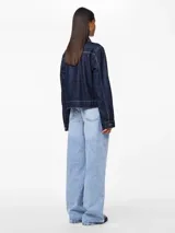 Chaqueta de denim azul oscuro con cuello camisero, cierre frontal con botones en forma de corazón, bolsillos delanteros y costuras en contraste color ocre.