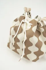 Bolso tipo bombonera tejido a crochet, con patrón geométrico en tonos rosa y marrón. Tiene cierre con cordón ajustable y correa de hombro.