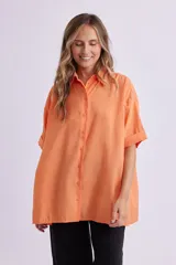 Camisa naranja fluida de manga corta con cuello clásico y cierre con botones.