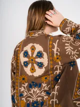 Chaqueta marrón con bordados florales en tonos azul y amarillo.
