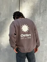 Buzo marrón con estampado en la espalda que incluye un sol, la palabra "Osten" y las frases "Empower Elevate Your" y "Boldness Strenght".