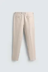 Pantalón de vestir color beige claro, confeccionado en lino, de corte recto, con bolsillos laterales y traseros.
