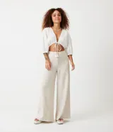 Blusa cropped blanca de laise texturizado con mangas 3/4 ajustadas y lazo en el bajo.