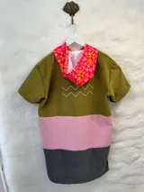 Poncho corto con capucha, color verde oliva con detalles en rosa y gris.
