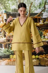 Blusa color crudo de lino con cuello en V y ribete marrón.