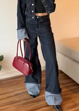 Pantalón de jean azul oscuro de corte ancho con dobladillo en color gris claro.