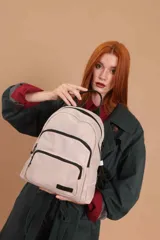 Mochila funcional color beige con detalles en negro, que incluye dos compartimentos con cierre y un bolsillo frontal para fácil acceso.