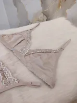 Conjunto de ropa interior color nude, compuesto por un corpiño triangular de algodón con detalles de encaje y una tanga a juego.
