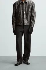 Pantalón negro de corte recto, con cintura elástica y cierre frontal de cremallera y botón. Presenta bolsillos delanteros y bolsillos traseros de vivo.