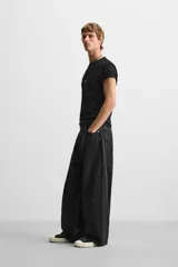 Pantalón de jean negro de corte amplio, con cinco bolsillos, efecto lavado y cierre frontal con cremallera y botón.
