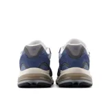 Championes New Balance modelo 2010, color azul marino y gris, con detalles en blanco y beige. Presentan una combinación de malla transpirable y gamuza, con el logo 'N' en el lateral y amortiguación visible en el talón.