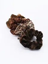 Set de cuatro scrunchies de tela en tonos marrones, con diferentes texturas y estampados: pana, terciopelo, animal print y lunares dorados.