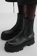 Bota Chelsea de cuero negro con elásticos laterales, tirador trasero y suela track de goma.