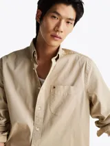 Camisa beige de corte amplio confeccionada en sarga de puro algodón teñido en prenda. Tiene cuello con botones, bolsillo de parche en el pecho y puños redondeados con botón.