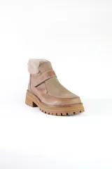 Bota corta de cuero color marrón con puntera y empeine de gamuza color beige. Tiene cuello de piel sintética color crema, cierre con velcro y suela track.