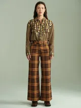Pantalón de corte ancho y tiro alto con estampado de cuadros en tonos negro, rojo y verde, con cierre y botones invisibles en el interior.