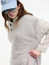 Chaleco sin mangas de cashmere color crema, con escote en V y tajos laterales.
