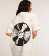 Remera alargada de algodón color crudo, con cuello redondo y mangas cortas. Presenta estampa de un disco de vinilo en la espalda y detalles de texto en el frente.