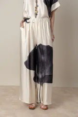 Pantalón palazzo color natural con estampado de hoja negra, de cintura elastizada.